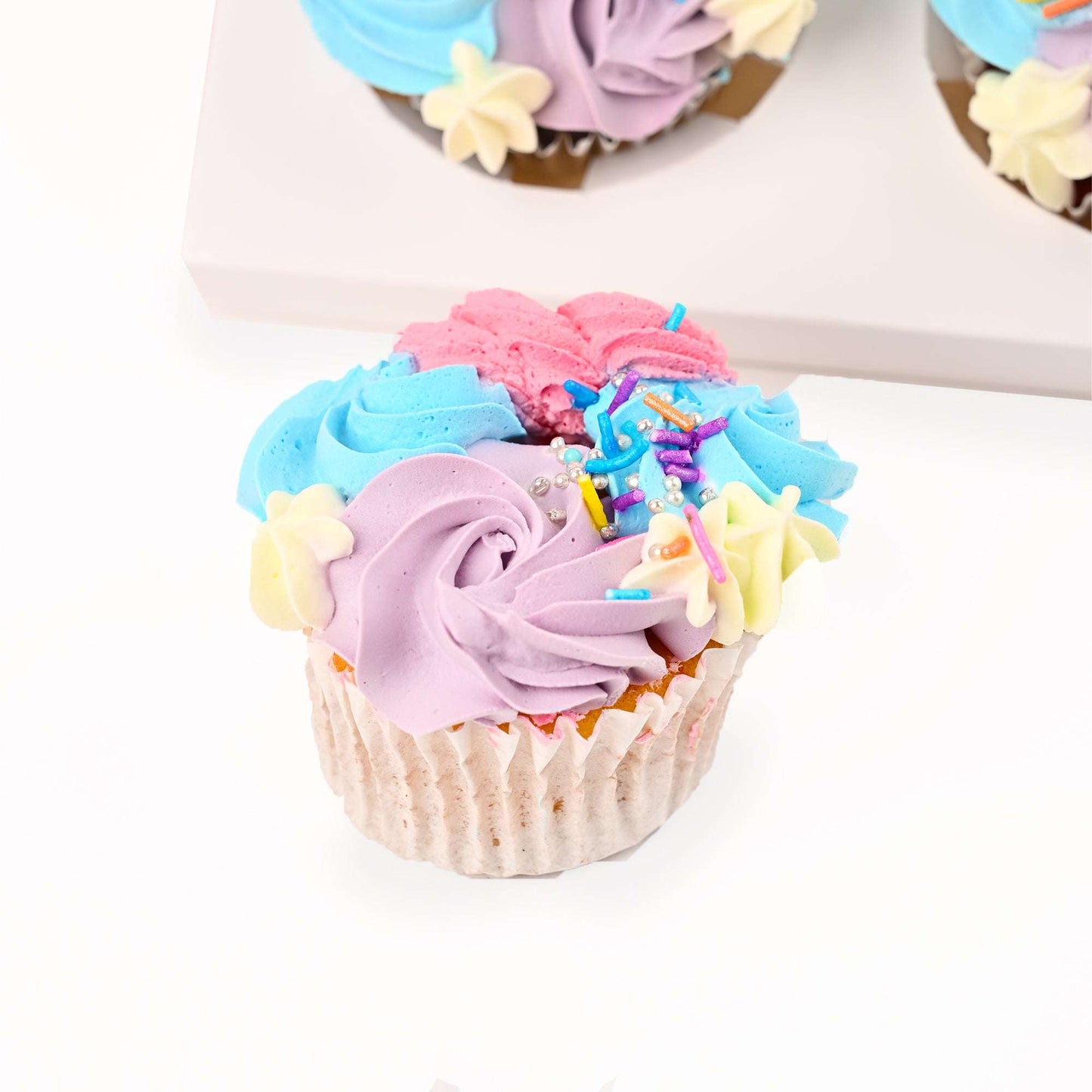 Close-up of a pastel buttercream cupcake with floral decoration
