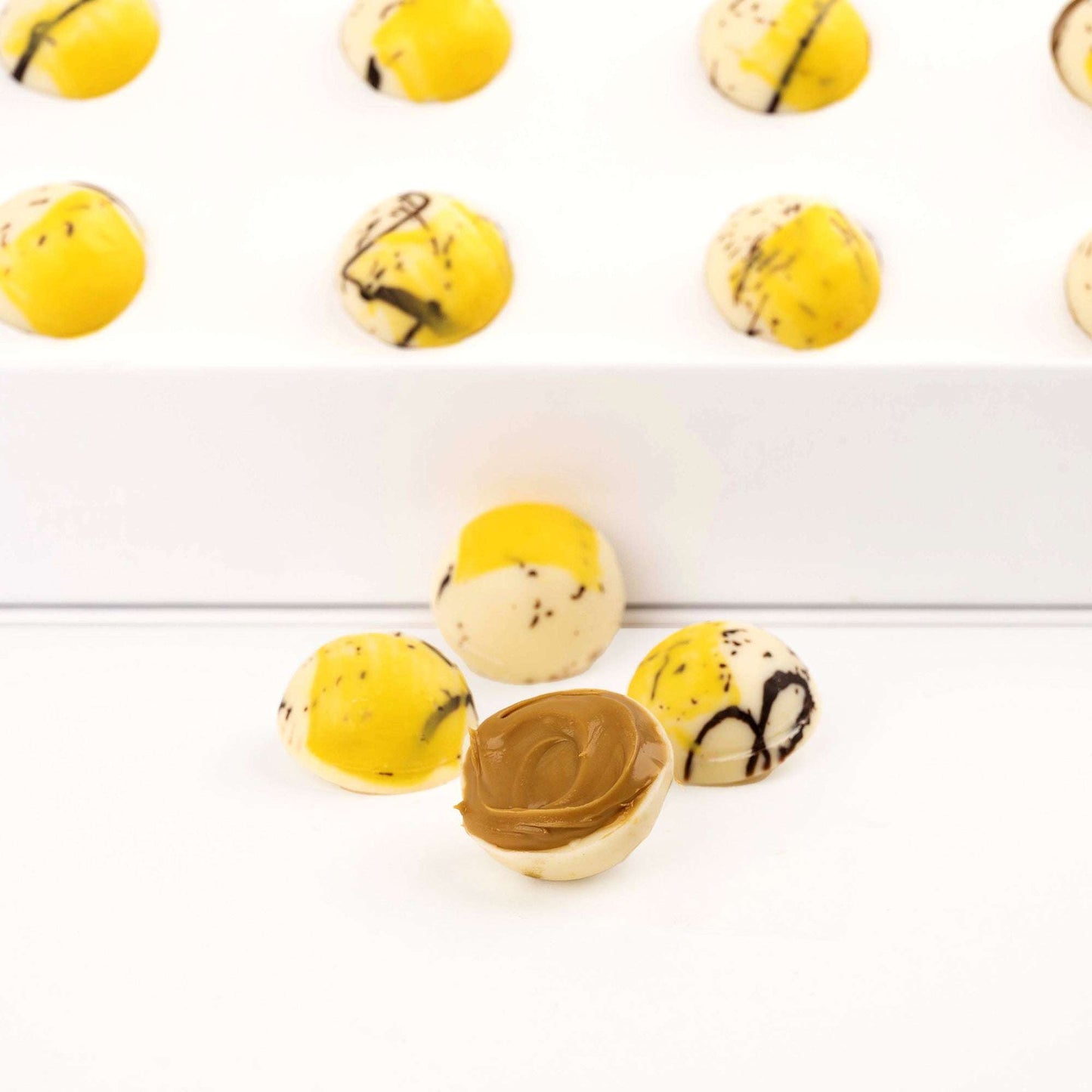 Close-up of yellow decorated chocolates, including one cut open to show the filling