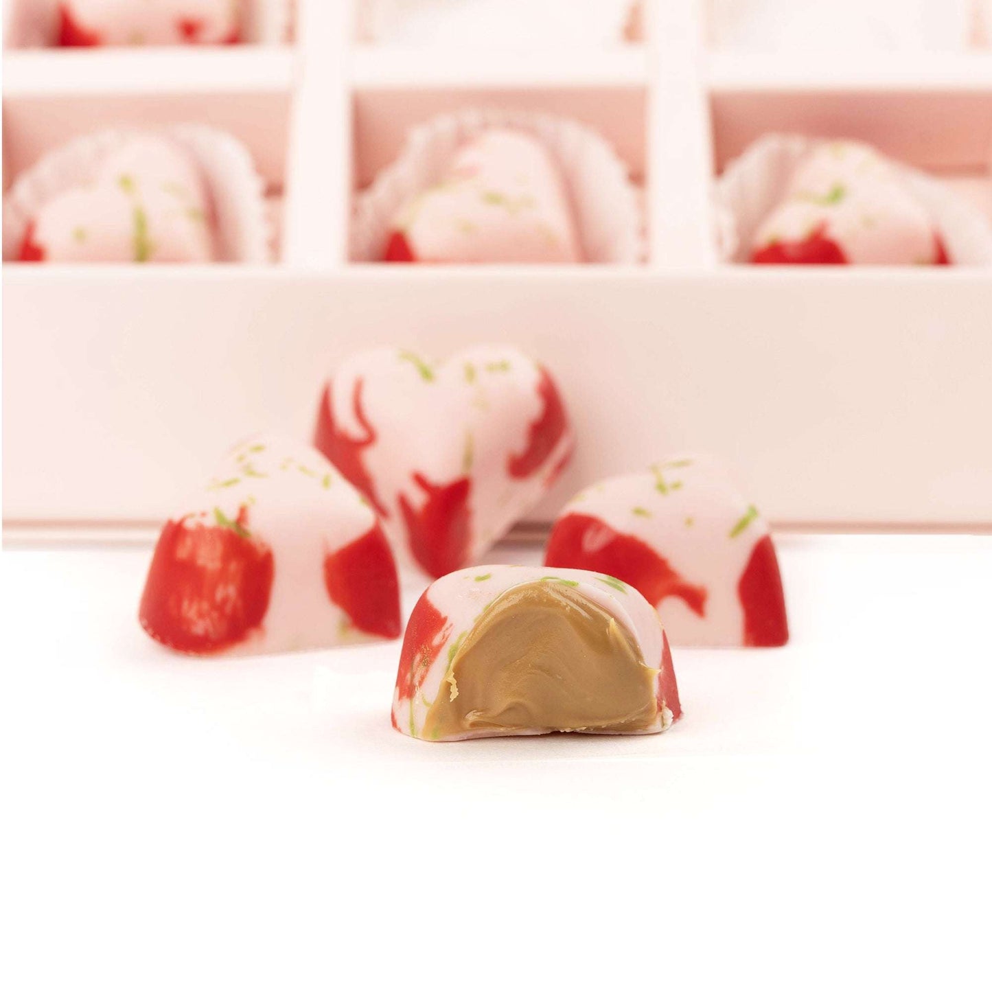 Close-up of strawberry-style chocolates, including one cut open to show the filling