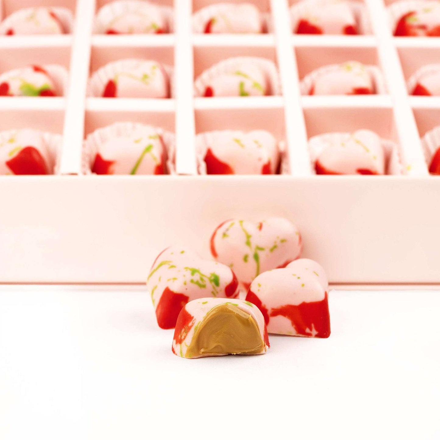 Close-up of strawberry-style chocolates, including one cut open to show the filling