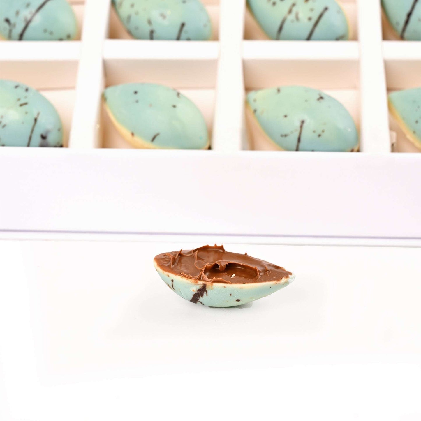 Close-up of blue decorated chocolates, including one cut open to show the filling