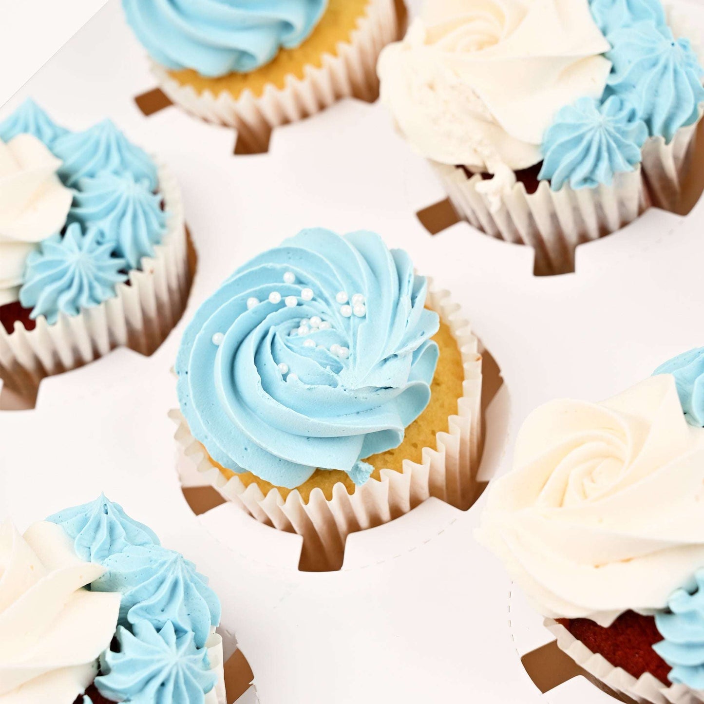 Close-up of blue and white buttercream cupcakes in the apology gift bundle