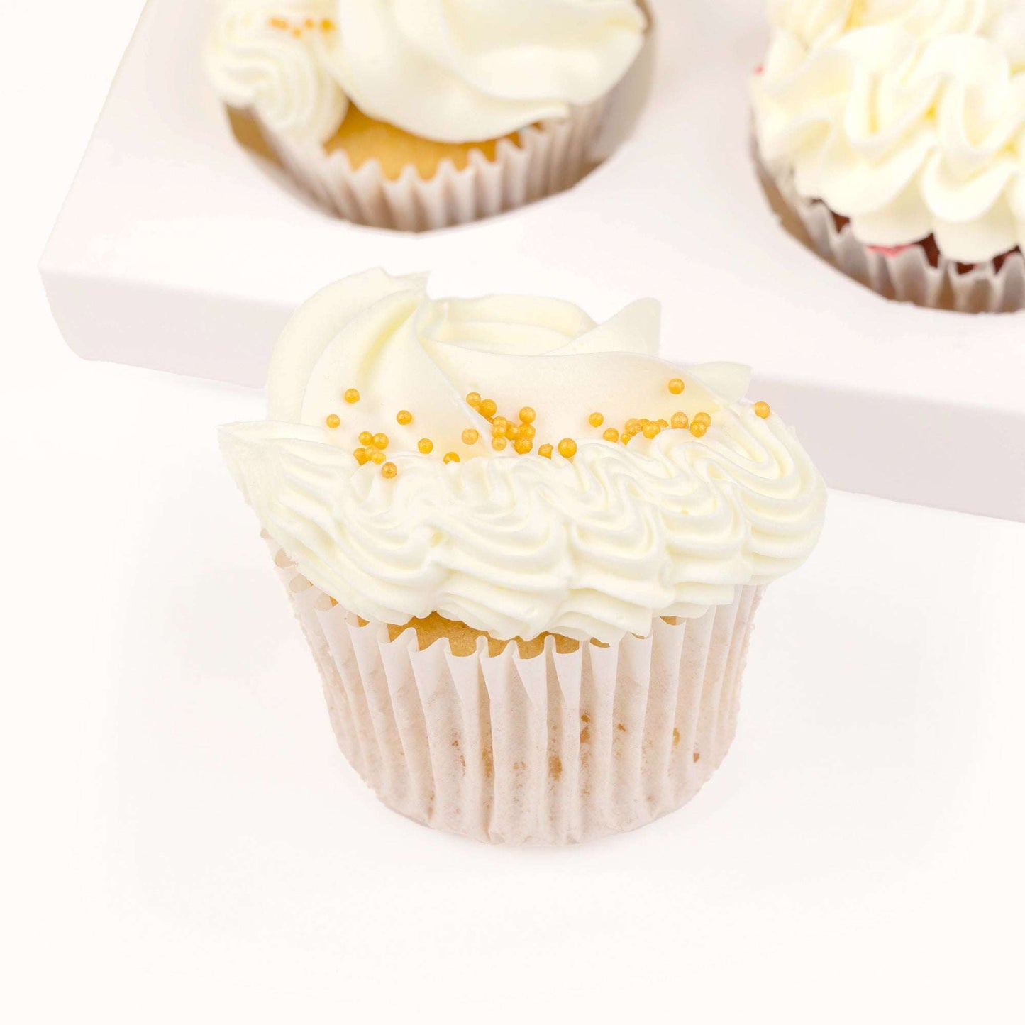 Close-up of a white and gold buttercream cupcake from the thank you hamper