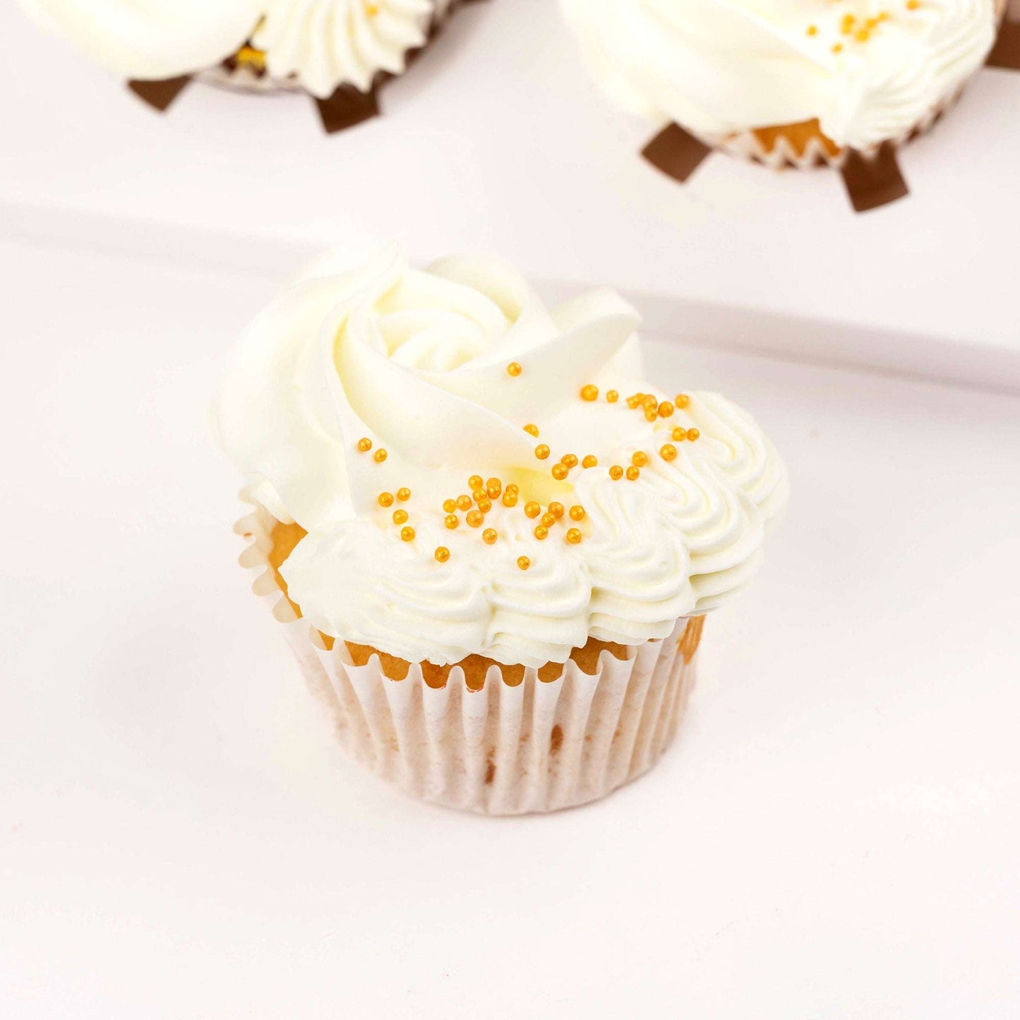 Close-up of a white and gold buttercream cupcake from the Classic Thank You Gift